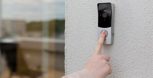 Person pressing the button of a video entry phone system doorbell